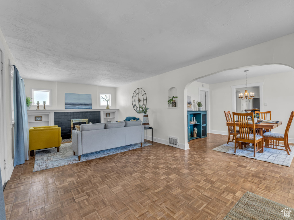 Living area with arched walkways, baseboards, a fireplace, and a chandelier