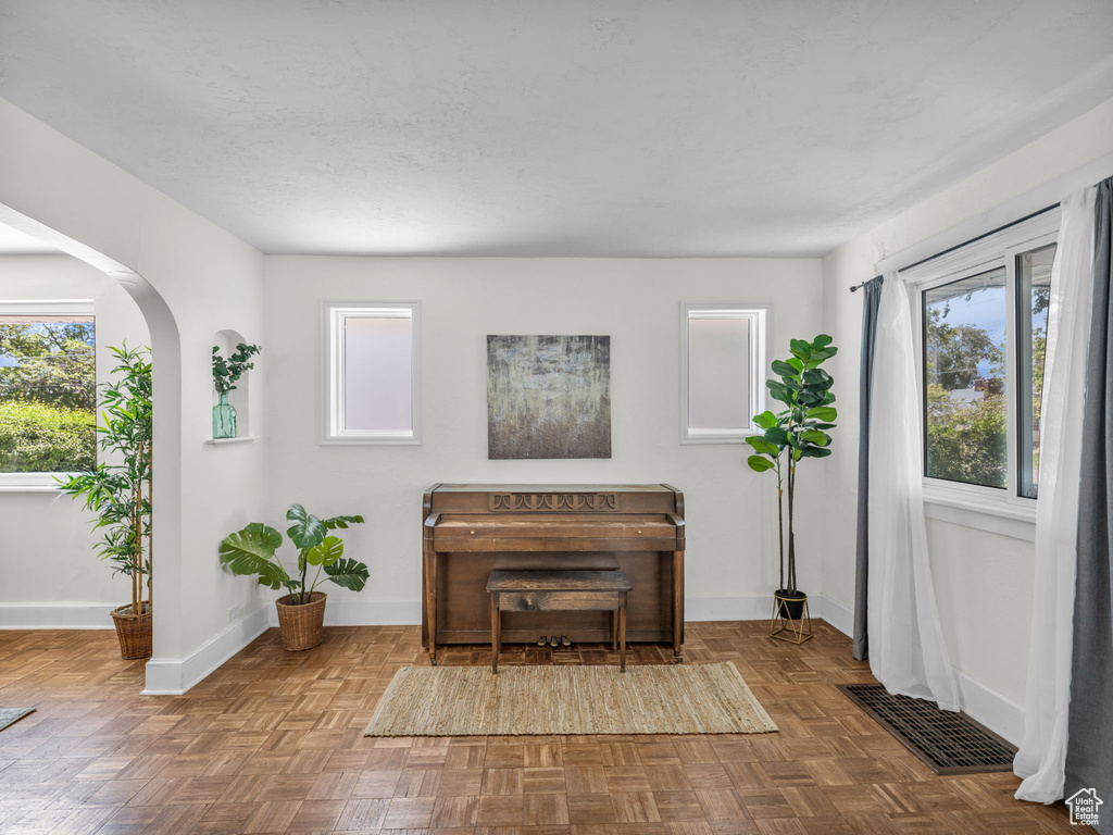 Living area with arched walkways, baseboards, and plenty of natural light