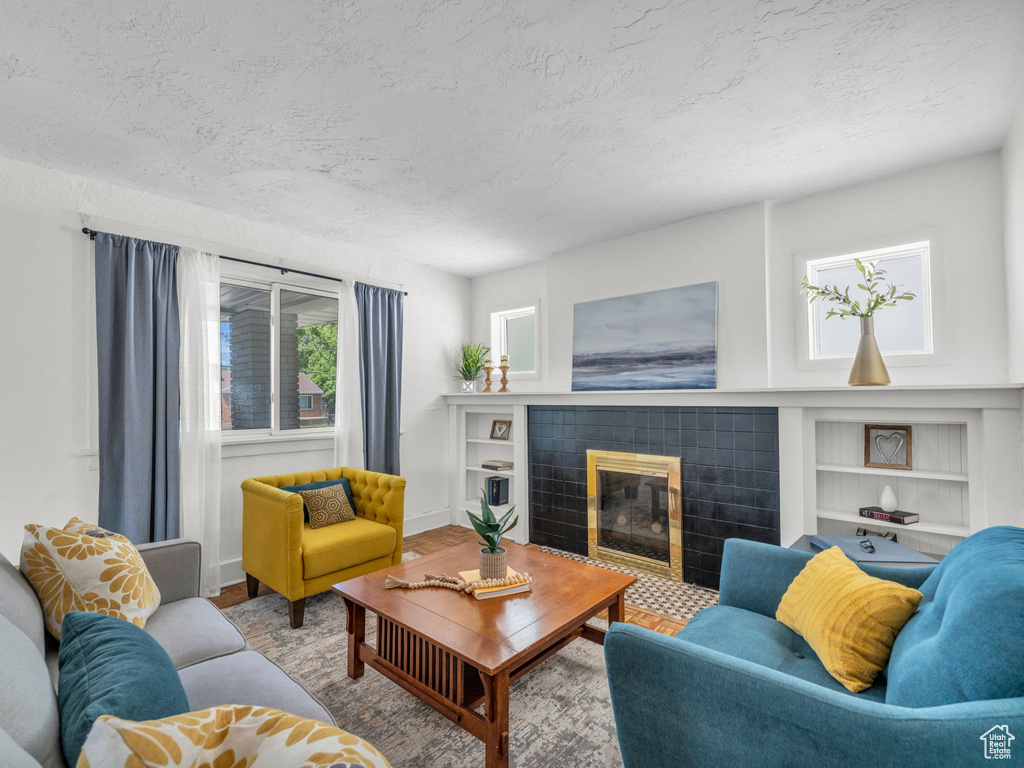 Living area featuring a textured ceiling, a fireplace, built in shelves, and baseboards