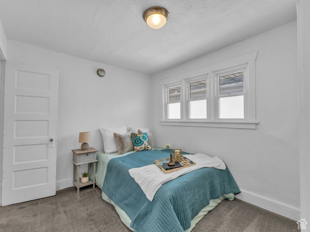 Bedroom featuring baseboards, carpet, and a textured ceiling