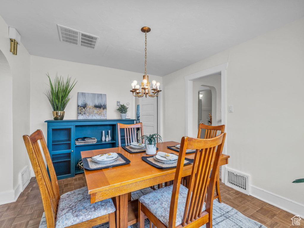 Dining room with arched walkways, a chandelier, and baseboards