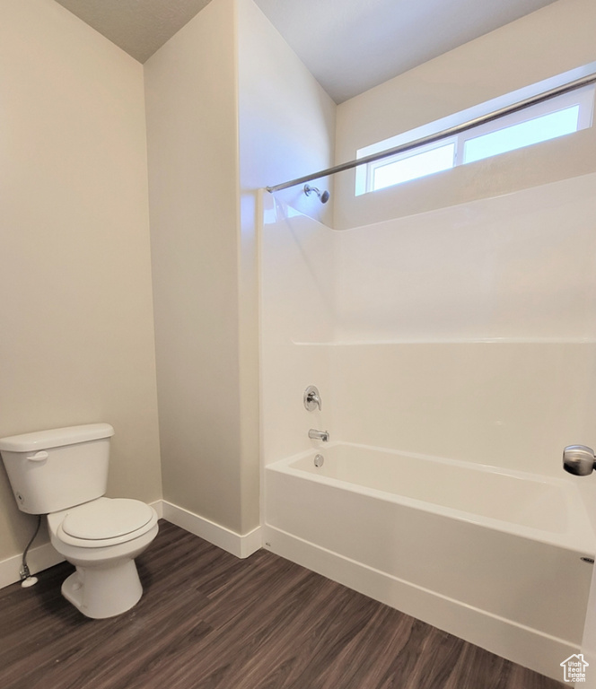 Full bath with baseboards, shower / bathtub combination, toilet, and wood finished floors