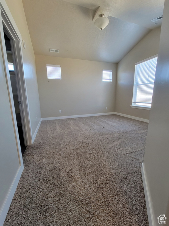 Unfurnished room featuring lofted ceiling, carpet floors, baseboards, and visible vents