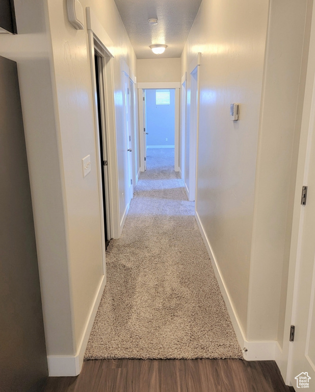 Corridor with baseboards, carpet flooring, and wood finished floors