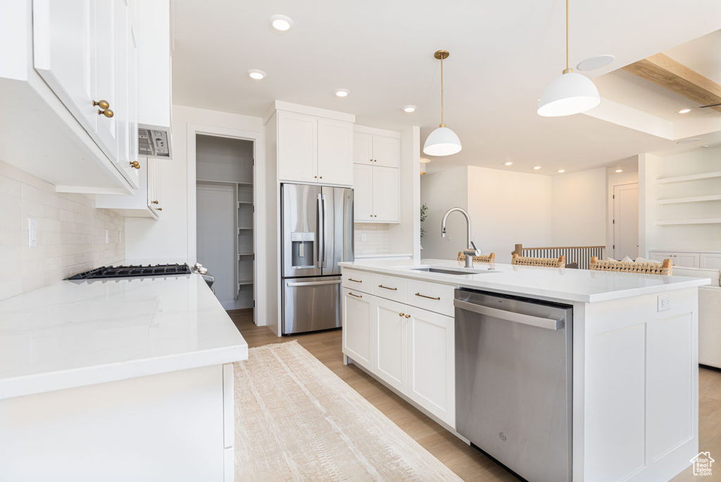 Kitchen featuring appliances with stainless steel finishes, a sink, backsplash, white cabinets, and recessed lighting