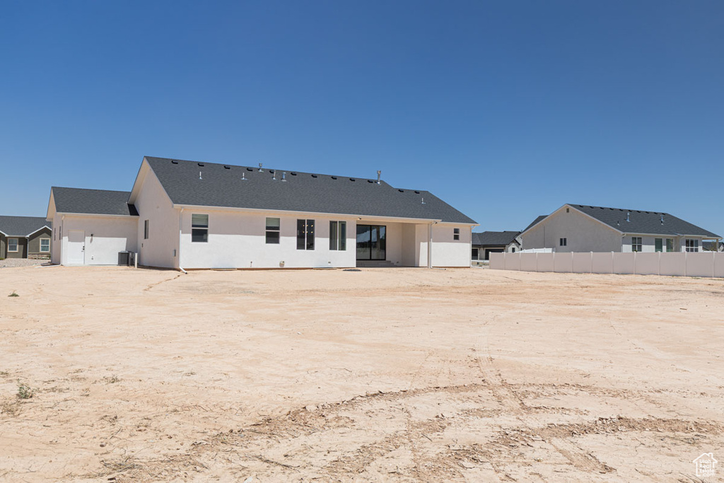 Back of house with fence, stucco siding, and central AC