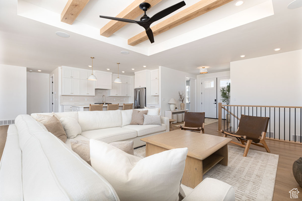 Living area featuring light wood finished floors, beam ceiling, a ceiling fan, and recessed lighting