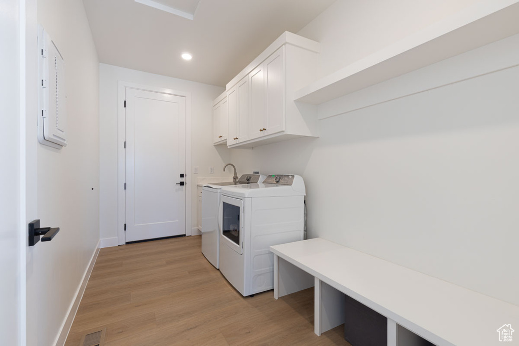 Laundry area featuring washing machine and clothes dryer, cabinet space, light wood-type flooring, recessed lighting, and baseboards