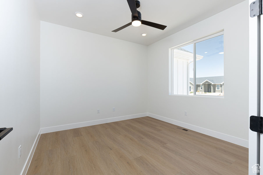Empty room with light wood-style floors, a ceiling fan, baseboards, and recessed lighting