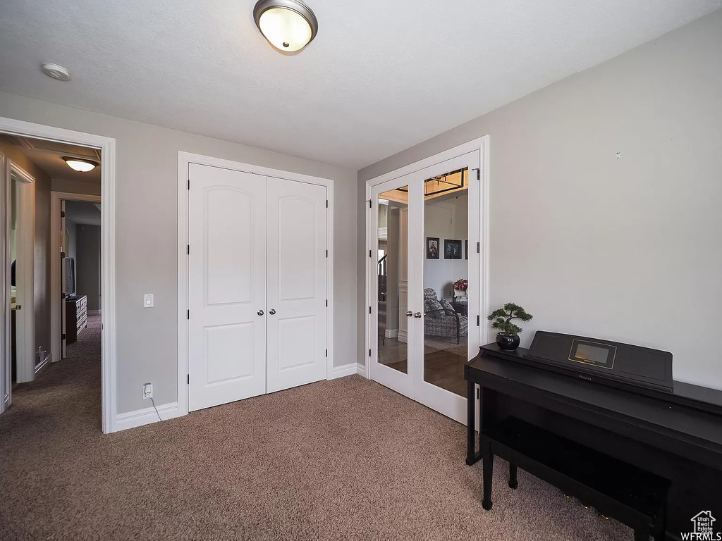 Carpeted bedroom with french doors, a closet, and baseboards