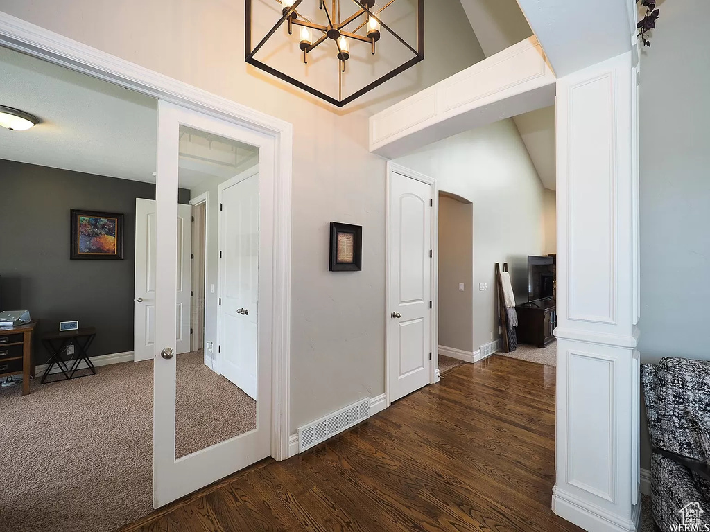 Corridor featuring dark wood finished floors, baseboards, and a chandelier
