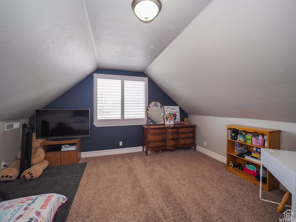 Carpeted bedroom with lofted ceiling, a textured ceiling, and baseboards