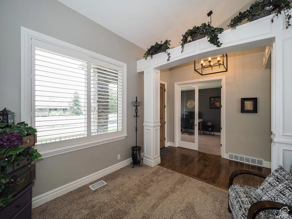 Living room with carpet flooring, a chandelier, baseboards, and french doors