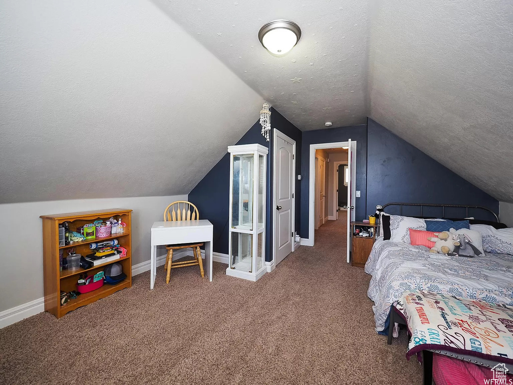 Carpeted bedroom with a textured ceiling, lofted ceiling, and baseboards
