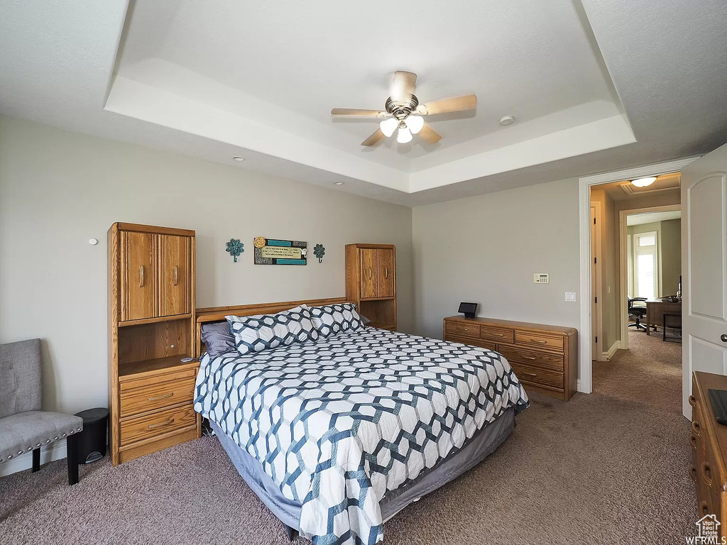 Bedroom with a tray ceiling, carpet flooring, and ceiling fan