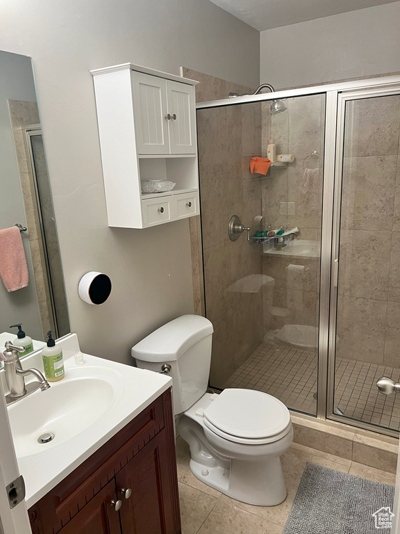 Bathroom with a shower stall, toilet, tile patterned flooring, and vanity