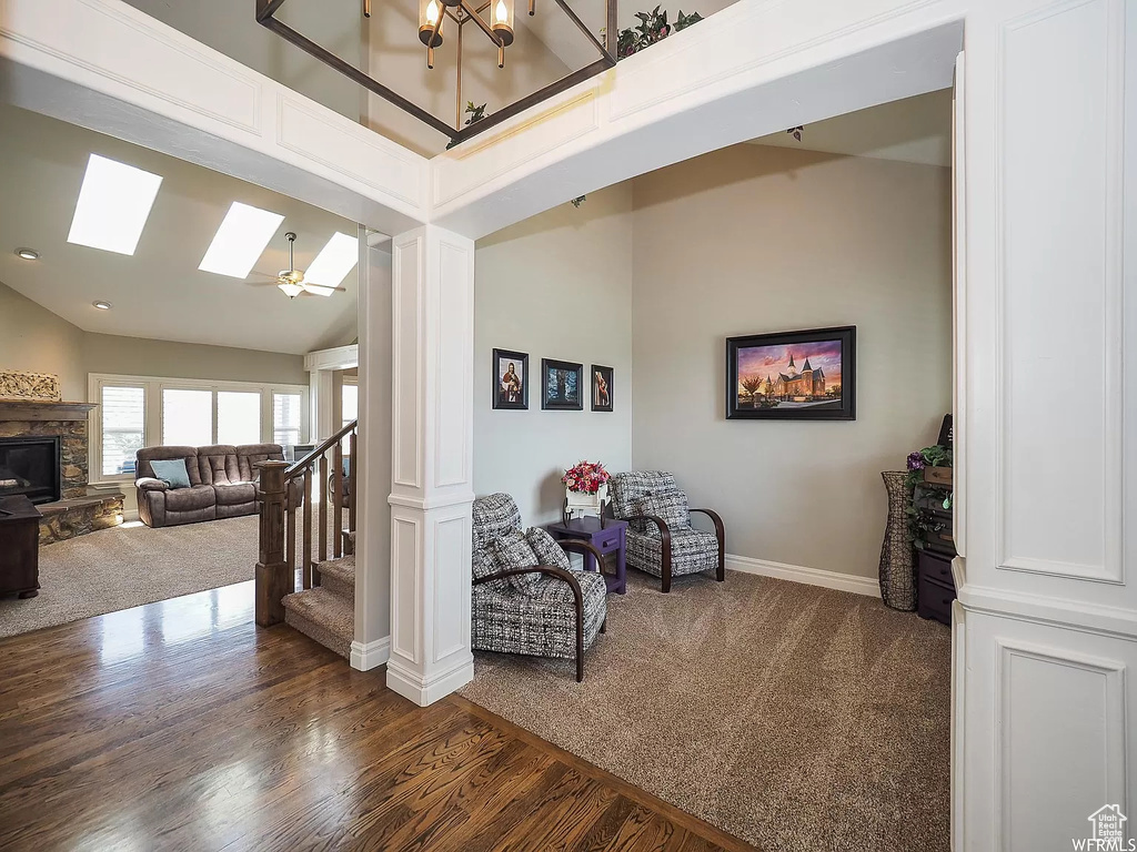 Sitting room featuring dark colored carpet, high vaulted ceiling, baseboards, dark wood-style floors, and a skylight