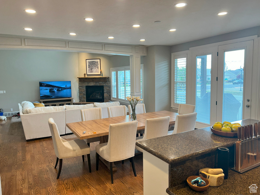 Dining area with recessed lighting, dark wood-type flooring, and a stone fireplace