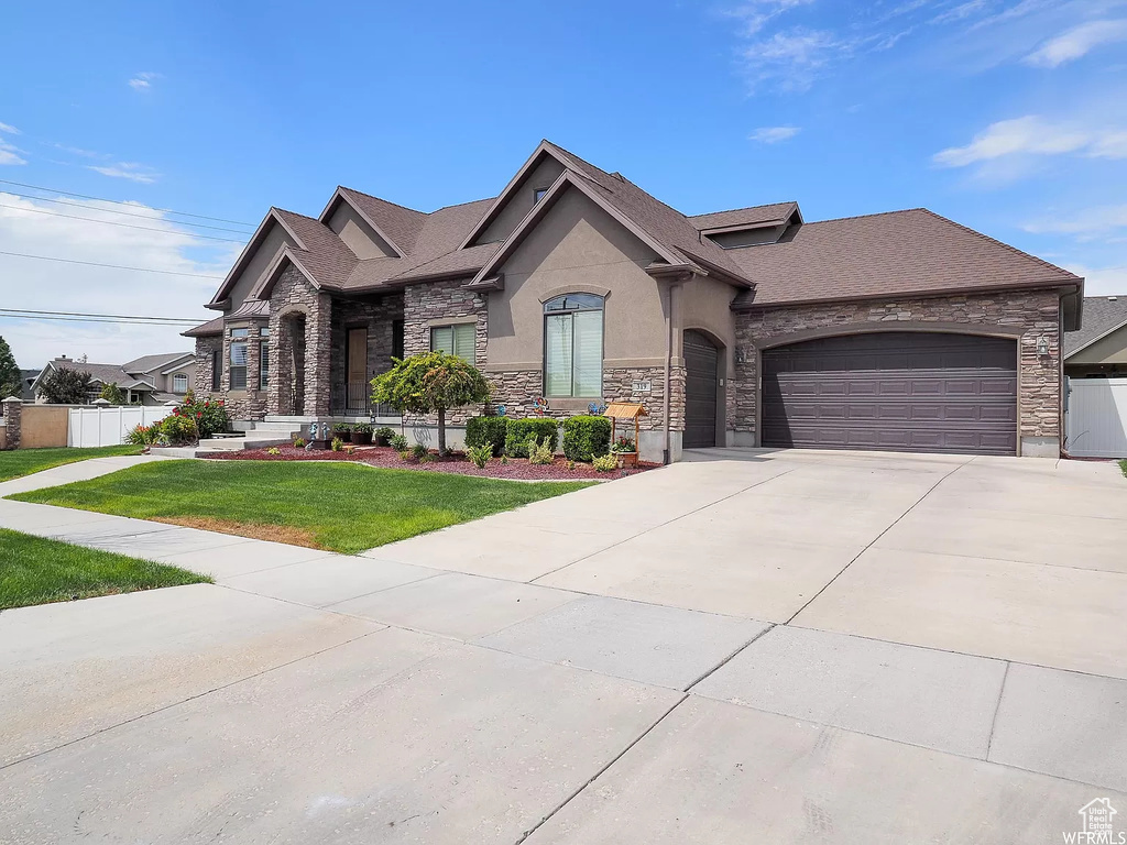 French provincial home featuring stone siding, stucco siding, an attached garage, and concrete driveway