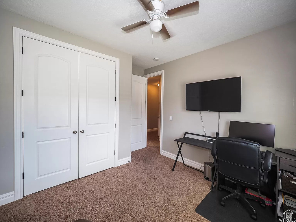 Carpeted office with ceiling fan and baseboards