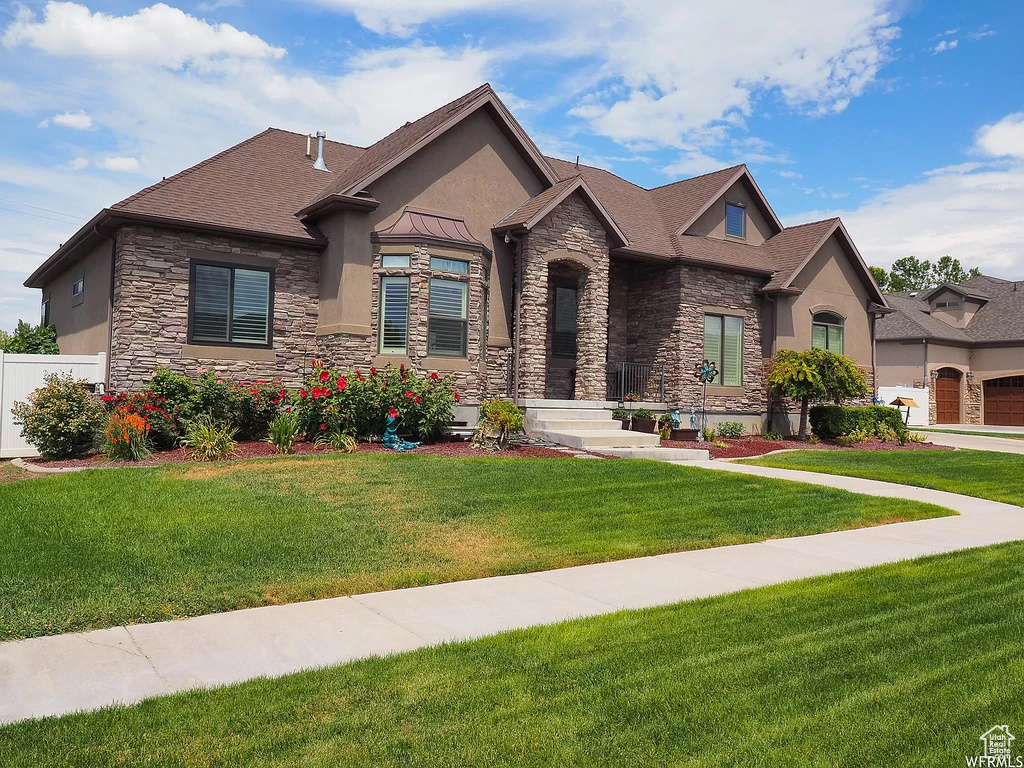 View of front of house featuring stucco siding, stone siding, and roof with shingles
