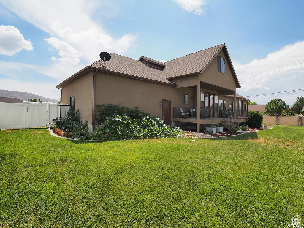 View of side of property featuring stucco siding, a gate, a deck, and roof with shingles