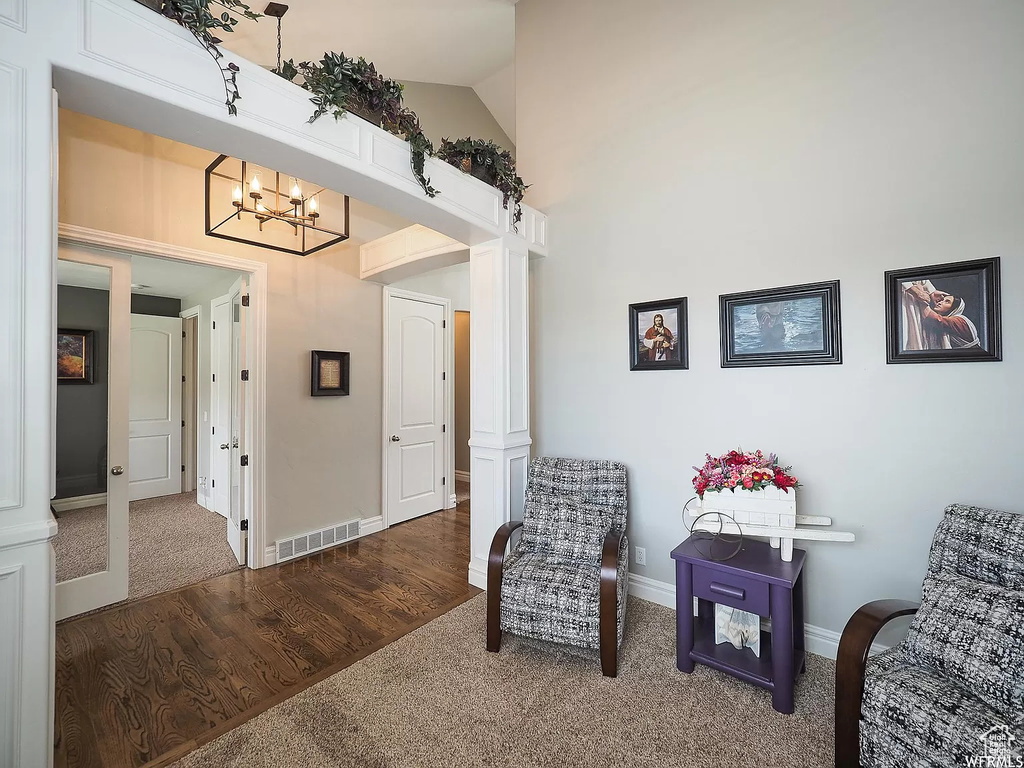Sitting room featuring carpet flooring, a chandelier, baseboards, high vaulted ceiling, and ornate columns