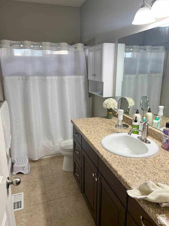 Bathroom featuring tile patterned floors, toilet, vanity, and curtained shower