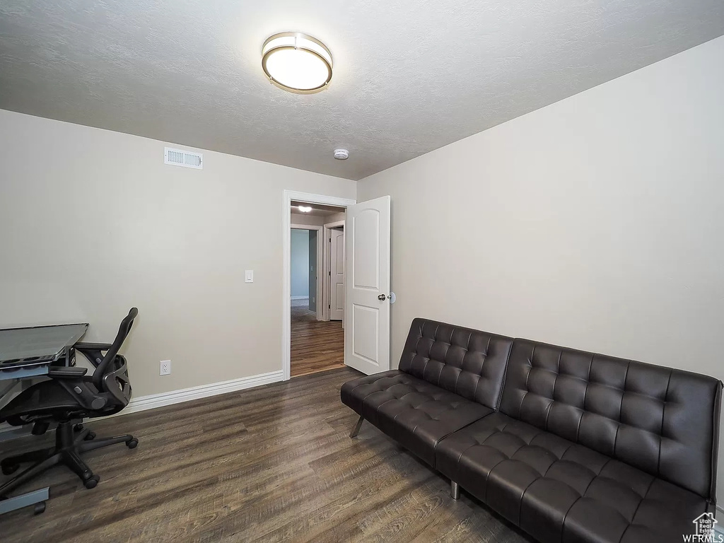 Office with wood finished floors, baseboards, and a textured ceiling
