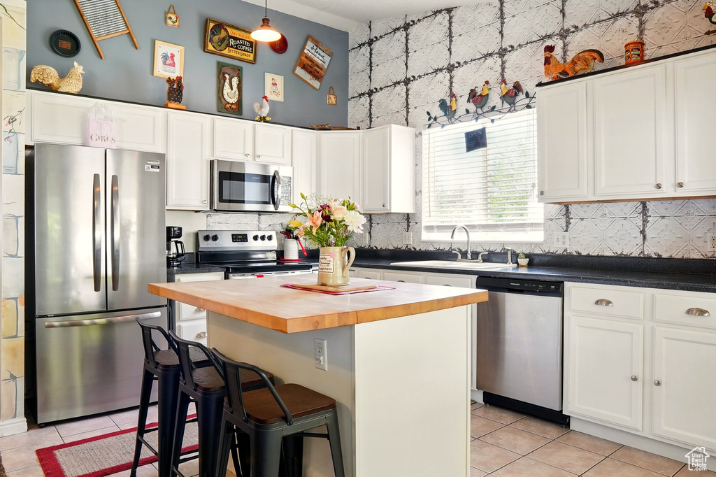 Kitchen with stainless steel appliances, wood counters, light tile patterned floors, and a sink