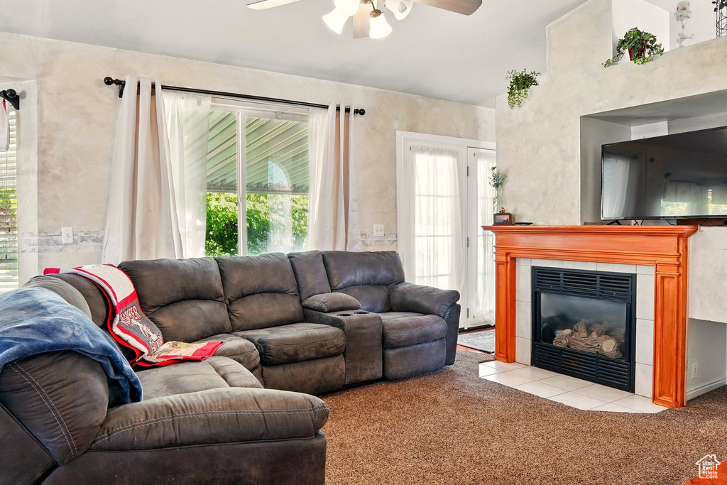 Carpeted living room featuring ceiling fan and a tile fireplace