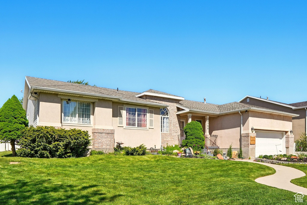 View of front of property featuring stucco siding, a garage, and a front yard