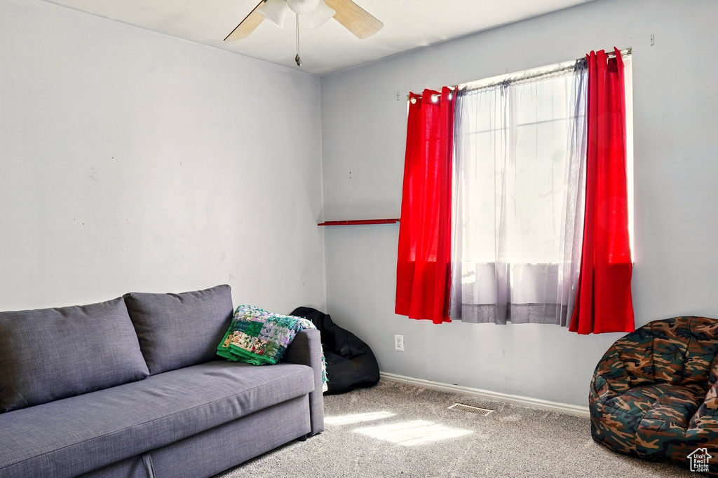 Carpeted living room featuring ceiling fan and baseboards