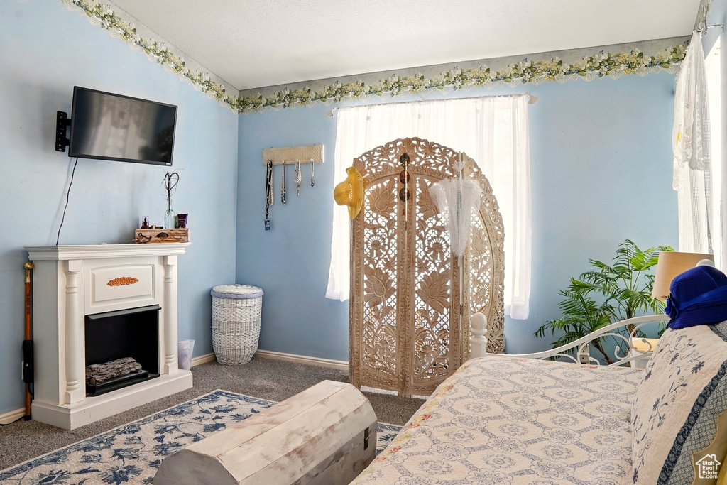Bedroom with carpet floors, baseboards, and a fireplace with raised hearth