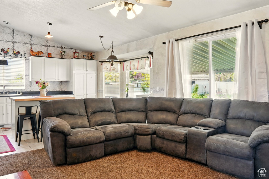 Living area with lofted ceiling, ceiling fan, and light tile patterned floors