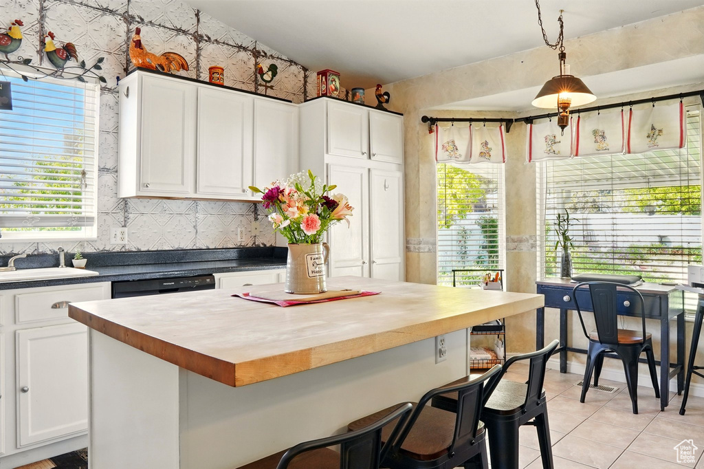 Kitchen featuring a sink, butcher block countertops, light tile patterned flooring, and white cabinetry
