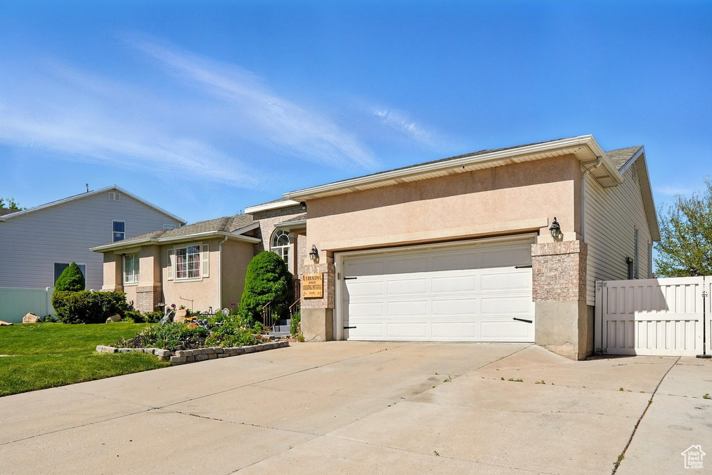 View of front of house with a garage, driveway, stucco siding, and stone siding
