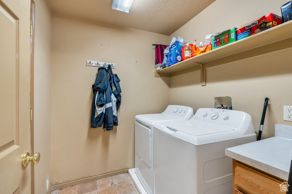 Clothes washing area featuring washer and dryer, baseboards, and a textured ceiling