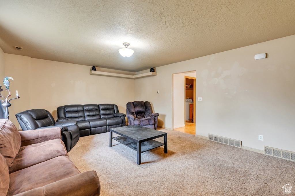 Living area featuring light carpet, a textured ceiling, and baseboards