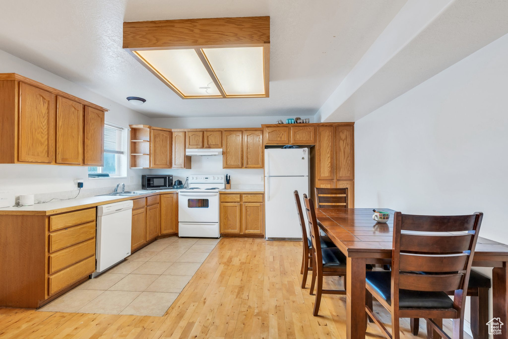 Kitchen with white appliances, a sink, light countertops, open shelves, and light wood-type flooring