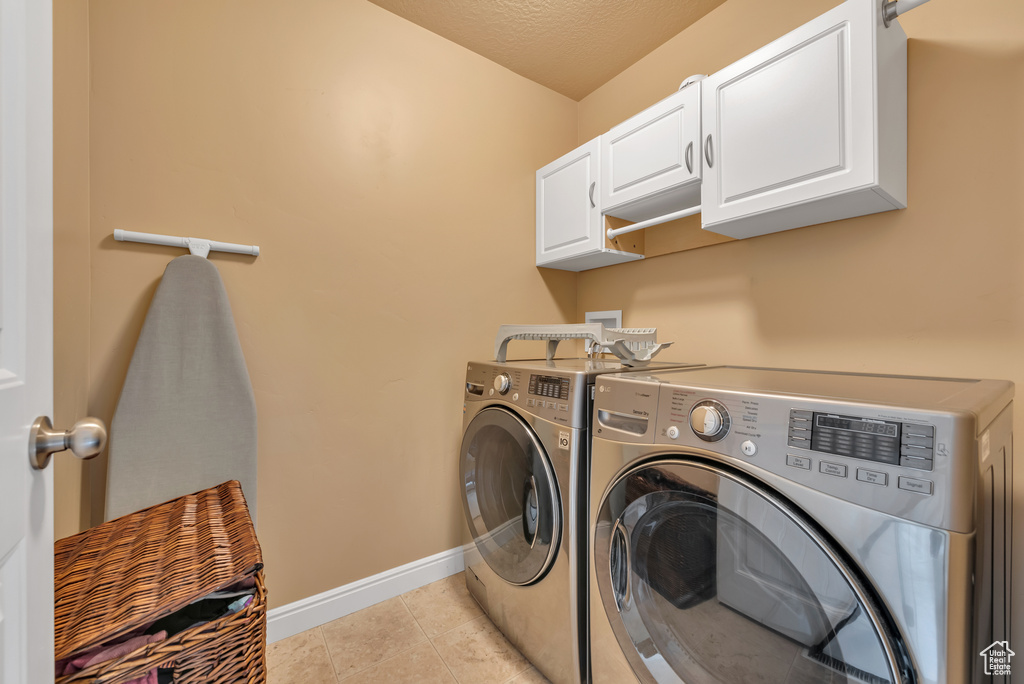 Laundry room featuring separate washer and dryer, baseboards, cabinet space, and light tile patterned flooring