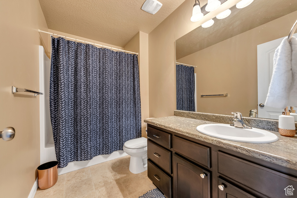 Full bath with toilet, vanity, shower / bath combo, and a textured ceiling