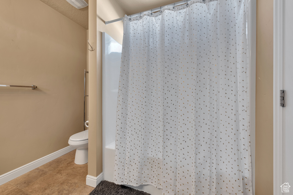 Full bathroom featuring tile patterned floors, baseboards, and toilet