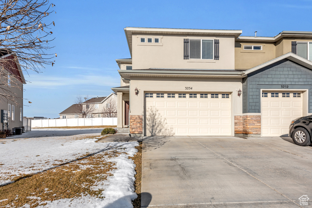 View of front of property with driveway, a garage, fence, and stone siding