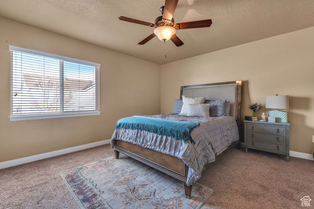 Bedroom with carpet, baseboards, a textured ceiling, and ceiling fan