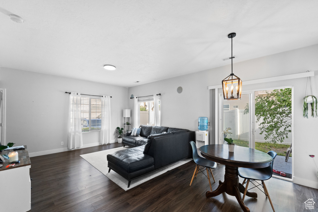 Living area featuring dark wood-type flooring, a chandelier, and baseboards