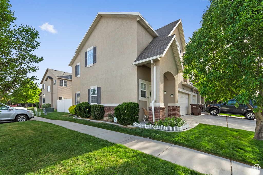 View of side of home with stucco siding, driveway, brick siding, and a shingled roof