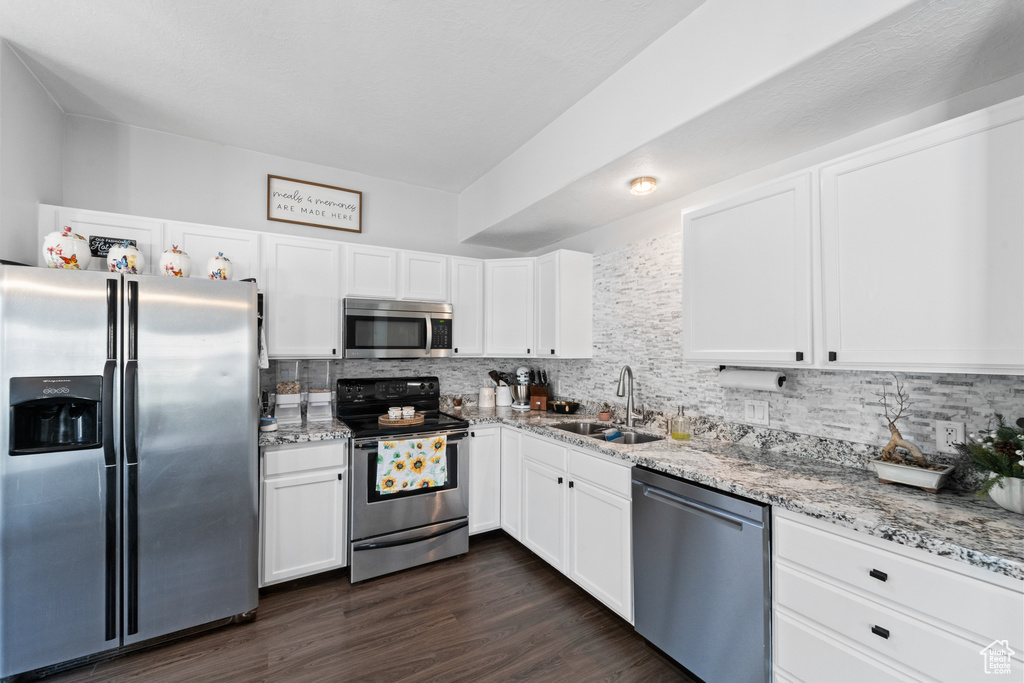 Kitchen featuring appliances with stainless steel finishes, a sink, tasteful backsplash, and light stone counters