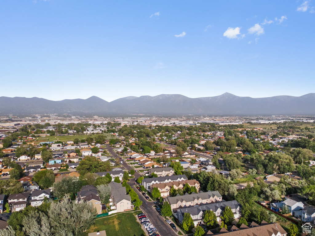 Aerial view of property and surrounding area featuring a mountain backdrop and nearby suburban area