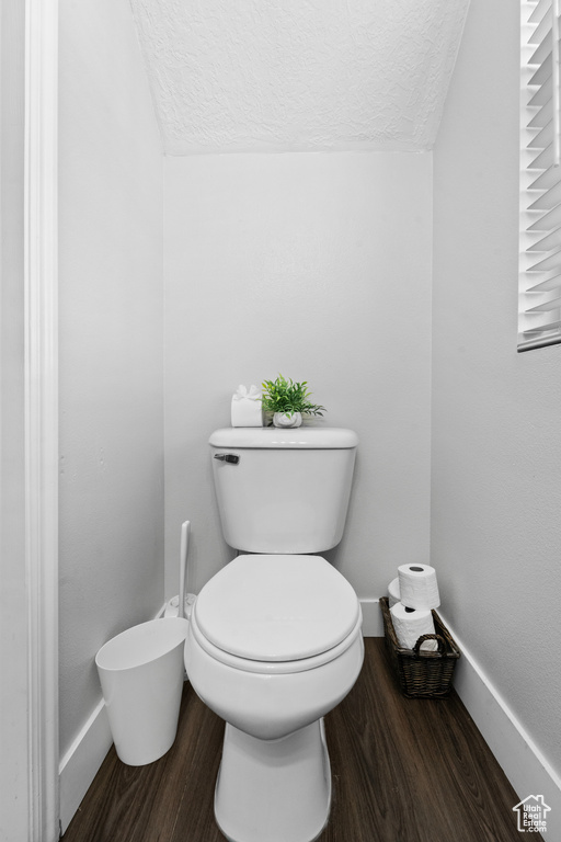 Bathroom with wood finished floors, a textured ceiling, toilet, and baseboards